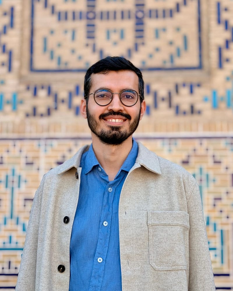 Selman Parlak smiling in front of a blue and gold tiled wall